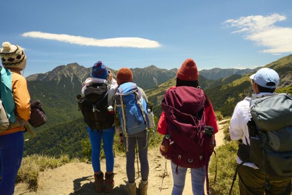 Hikers stand on top of a mountain looking at view.